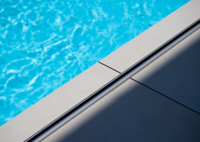 Coverseal-landscape3 Világoskék medence vize és világosszürke csempe találkozása, árnyékkal a csempén.