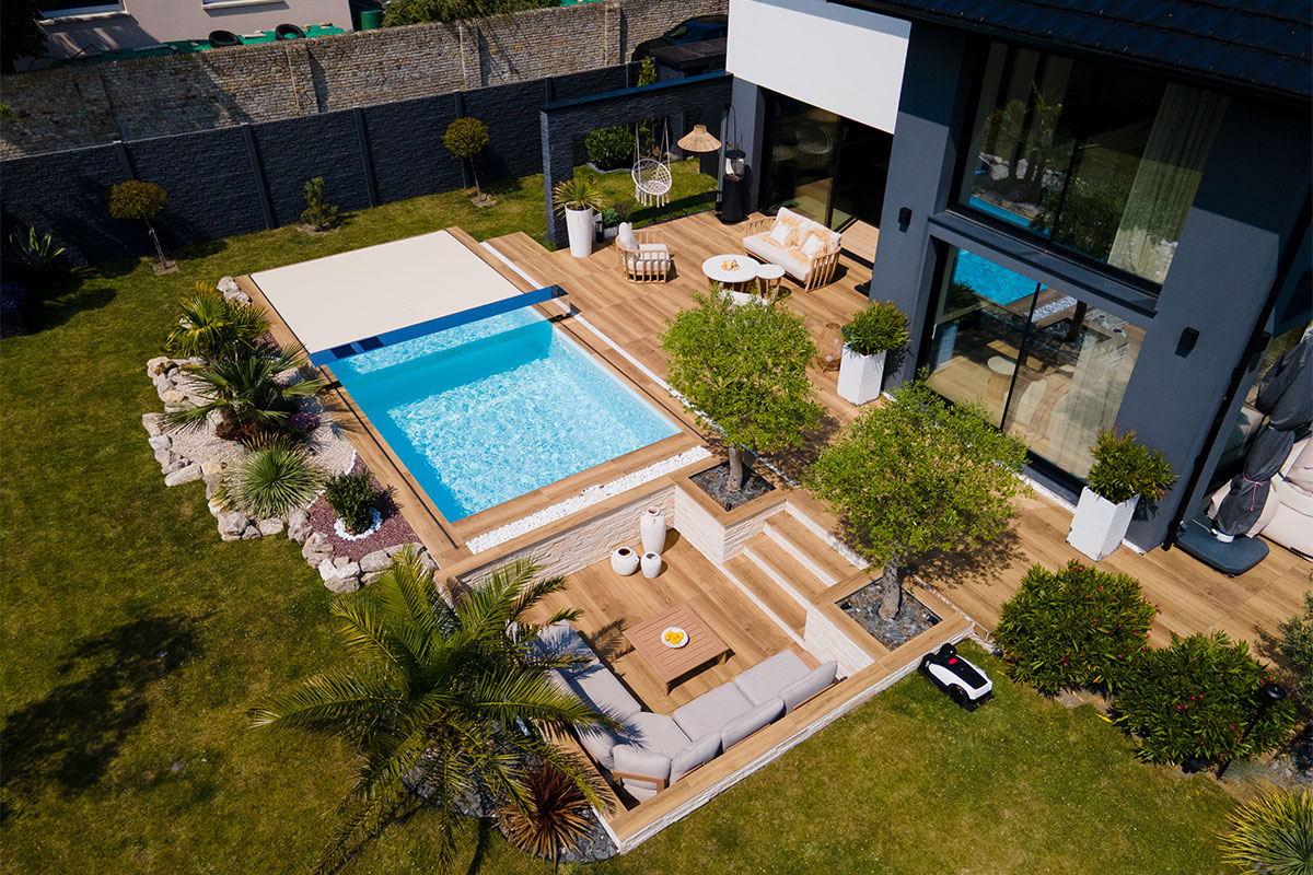 Piscine contemporaine partiellement couverte par une Coverseal, entourée d’une terrasse en bois clair et d’un coin lounge élégant.