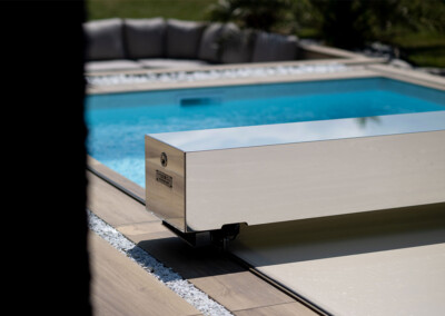 Kerti medence fedéllel, körülötte fa terasz és szürke kanapé.